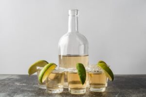 Botella de tequila y tragos servidos con limón